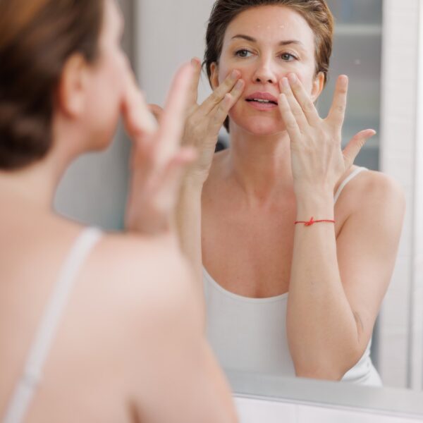 A woman inspecting congested pores on her nose in the mirror