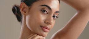 Woman with glowing skin resting her chin on her hand
