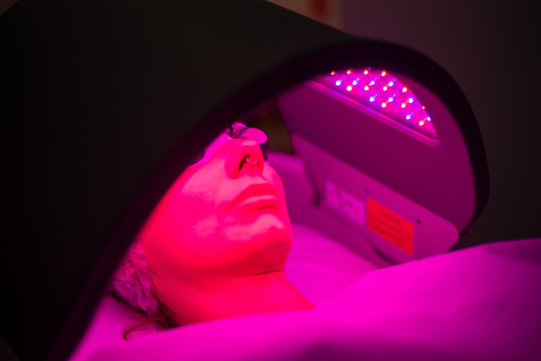 Patient relaxing under an LED light therapy panel at Regents Park Aesthetics