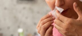 Woman removing a wax strip from her upper lip at home
