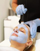 Practitioner applying a chemical peel mask with a brush
