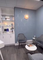 The clinic reception with grey velvet chairs and the blue geometric wall panel