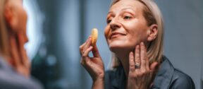 A woman applying moisturiser to her face at home